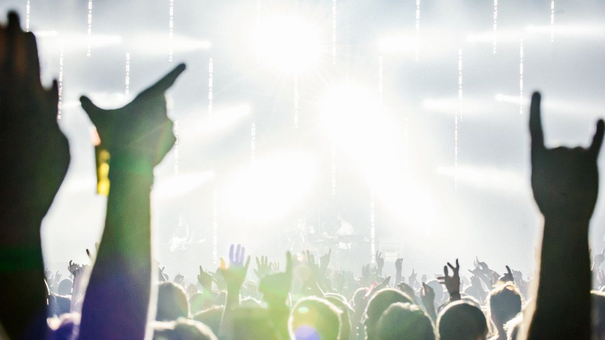 Público de un concierto de rock con los cuernos en alto delante de los focos