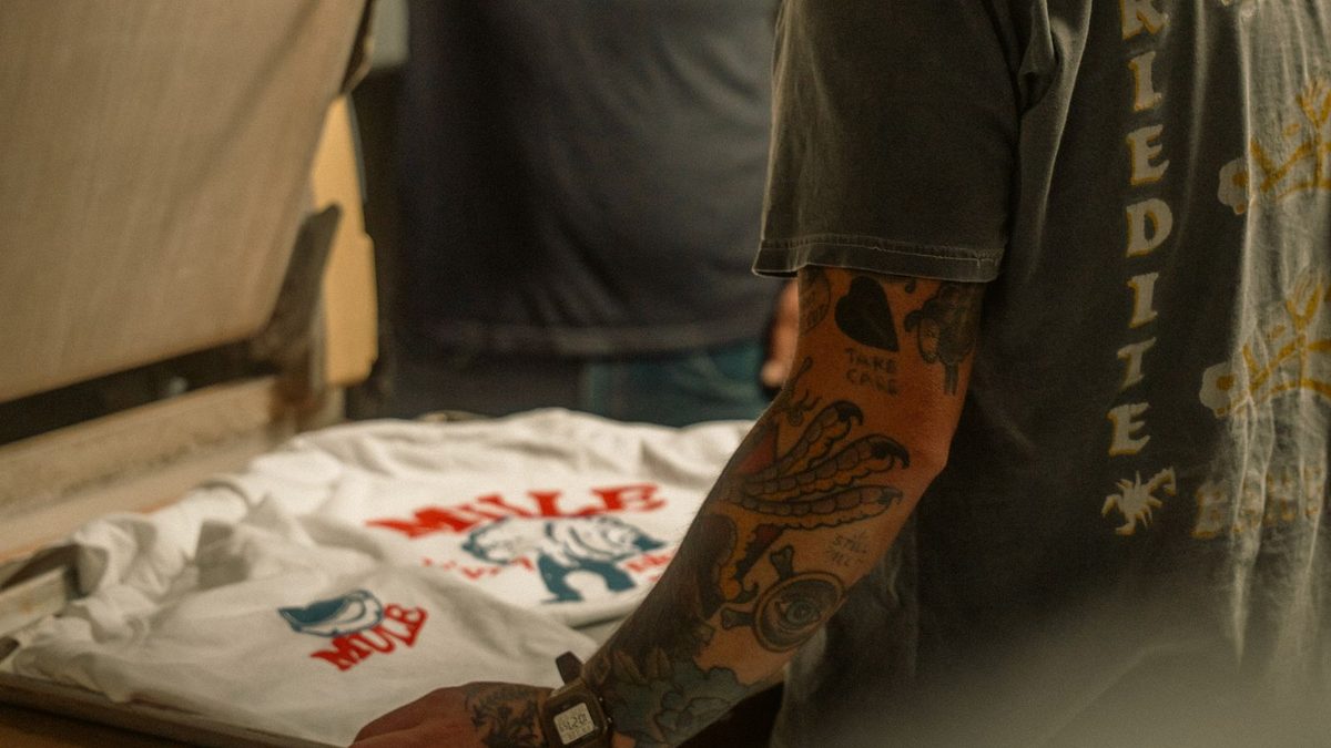 Dos personas estampando una camiseta en un taller de serigrafía